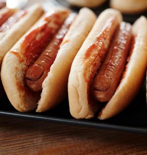 Row of hot dogs topped with ketchup, showcasing a savory snack in a close-up view.